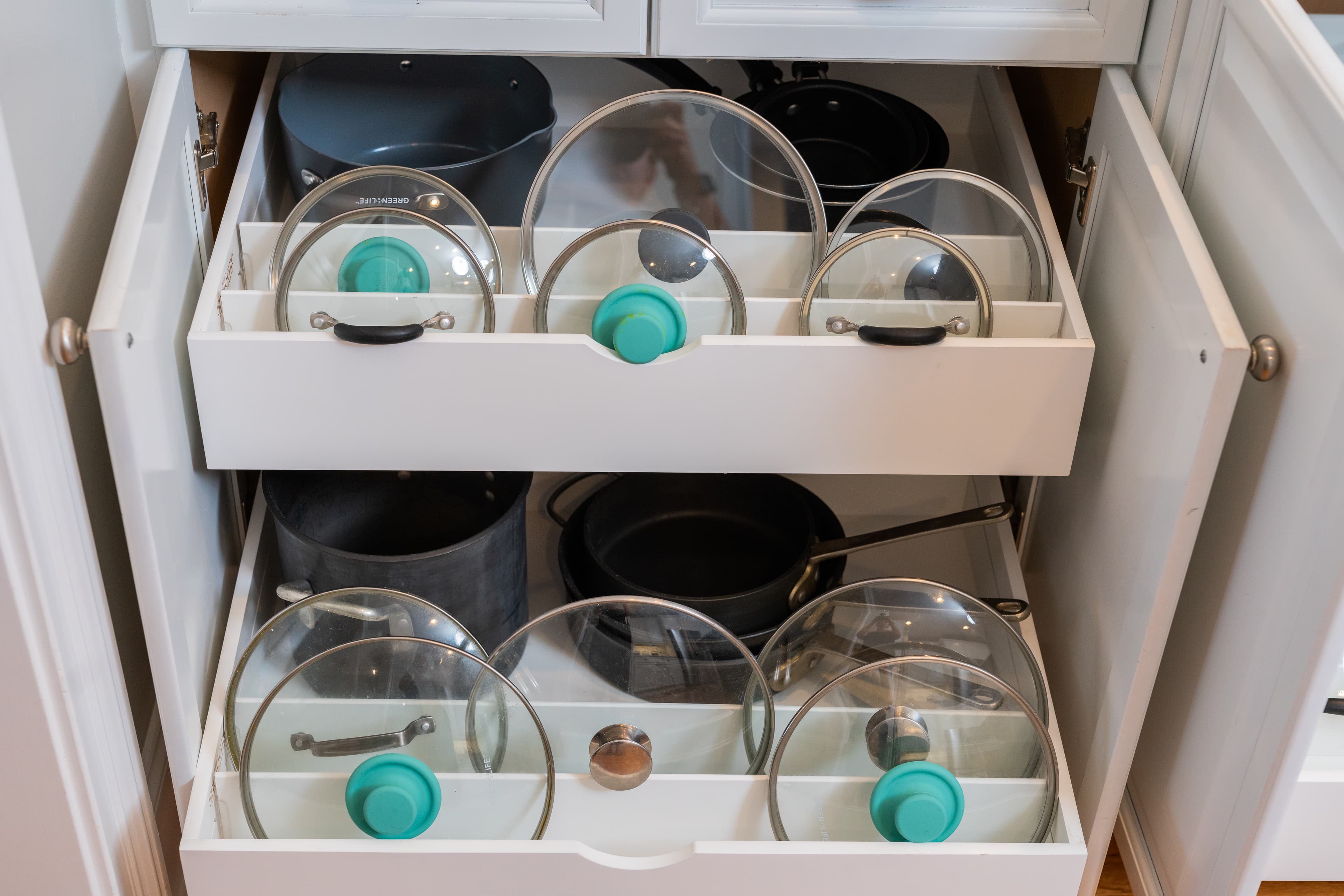 Pots and pan lids organized on white pull-out shelf
